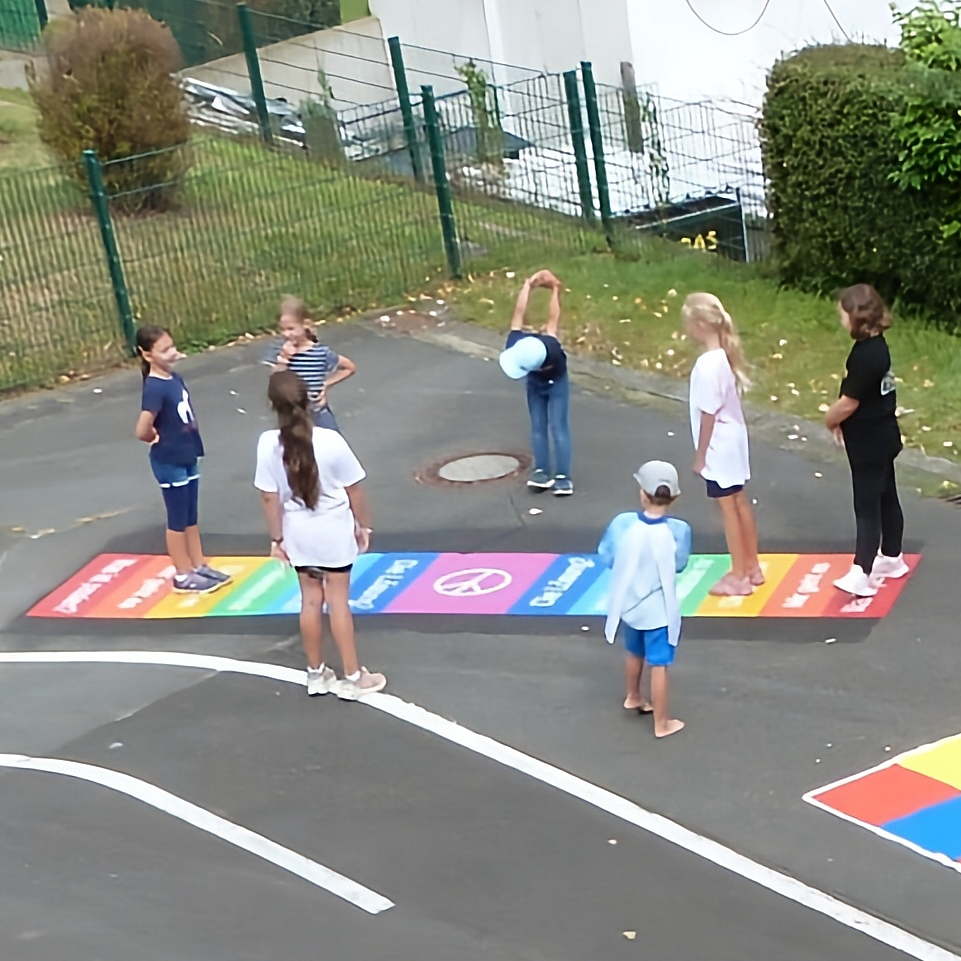 Kinder auf Schulhof und dem Friedensteppich